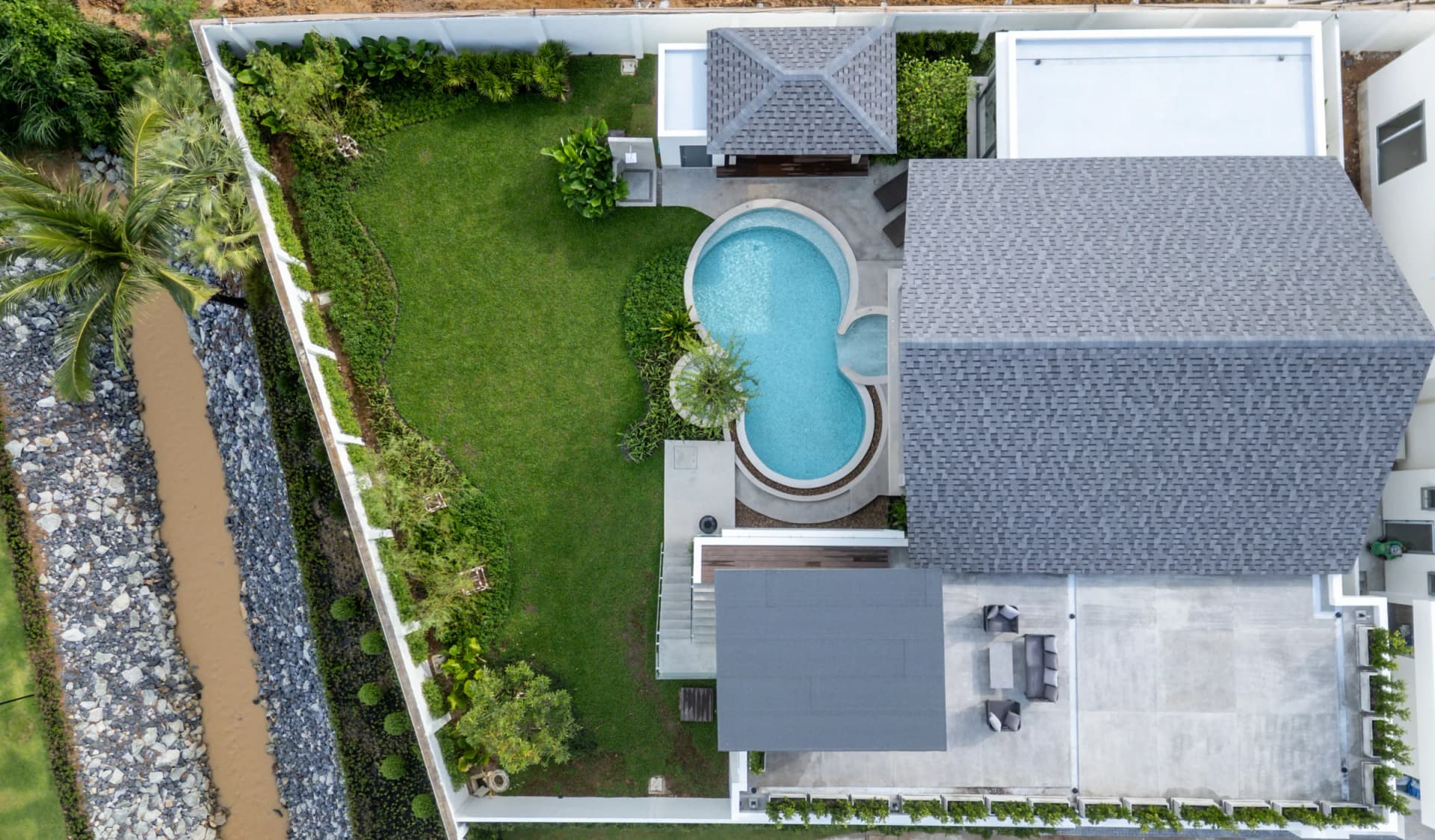 One plot from above: grey shingle roof, roof skydeck, figure-eight pool and lawn